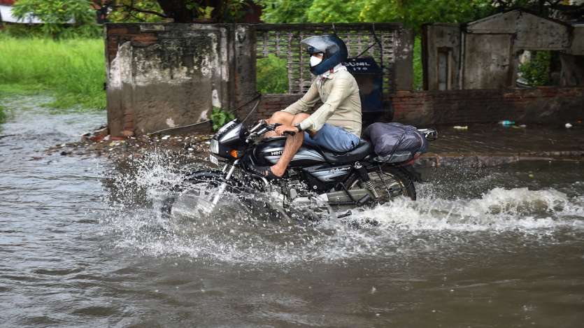 A commuter wades through a waterlogged street due to heavy rains, near ITO in New Delhi.