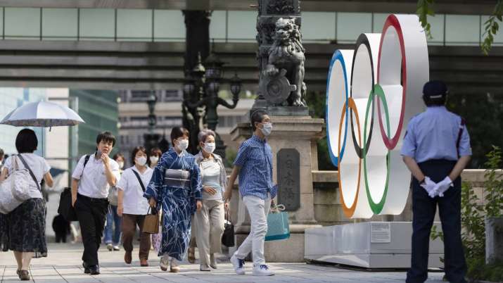 People walk by the Olympic rings installed by the Nippon Bashi bridge in Tokyo